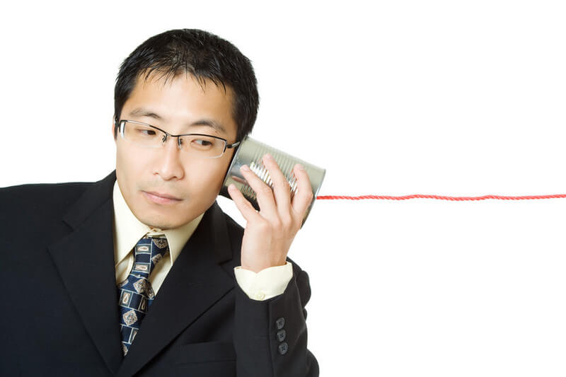 An isolated shot of a businessman listening to a tin can phone
